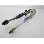 Ornate white metal sugar tongs with cherubs, fruit and vines decoration, 17cm long