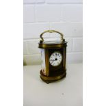 A brass cased clock with an enamelled panel to side on four bun feet (a/f), height 17cm