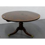 A mahogany veneered circle top dining table on a baluster column and reeded tripod supports