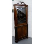 A corner cabinet, the swan neck pediment above a glazed astragal panel door enclosing a shelved