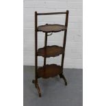 A mahogany three tier folding cake stand, each leaf with pie crust edge raised on trestle