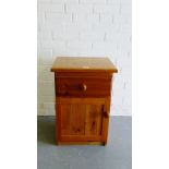 A pine bedside with single drawer and cupboard door