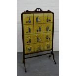 A fire screen with a scroll carved top over glazed panel containing an oriental panel depicting