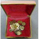 A small collection of foreign coins in a pink leather box