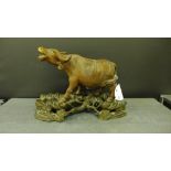 A carved wood figure of a Water Buffalo, modelled standing on a shaped naturalistic hardwood