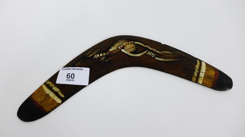 A miniature wooden painted boomerang bearing a label for the Queensland Aboriginal Creations