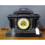 A Victorian black slate mantle clock with a white enamel chapter ring with Roman numerals flanked by