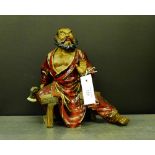 A Japanese stoneware and red glazed figure of an axe man, modelled seated on a trestle stool, 28cm