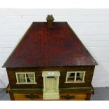 An early 20th century dolls house, the lift up top revealing an interior with four rooms, one