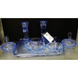 An early 20th century moulded blue glass dressing table set comprising candlesticks, ring stand, two