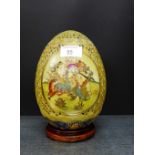 A Chinese pottery egg, pierced brown and painted with figures and coloured enamels on a turned