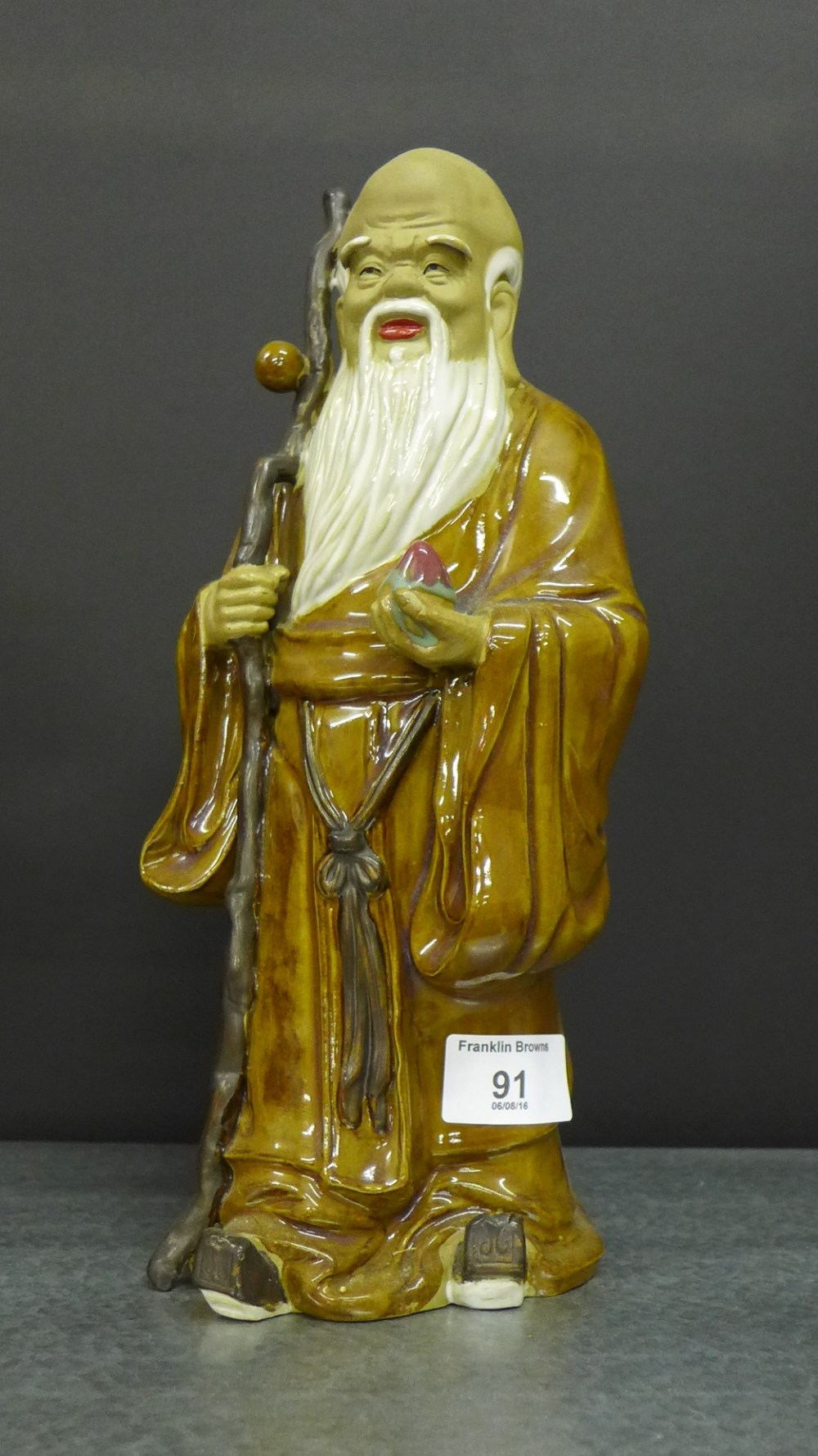 A Chinese brown glazed stoneware figure of a Lohan, 29cm high