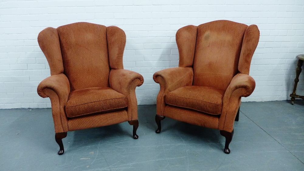 A pair of terracotta upholstered wing armchairs on cabriole mahogany supports, 110 x 90cm (2)