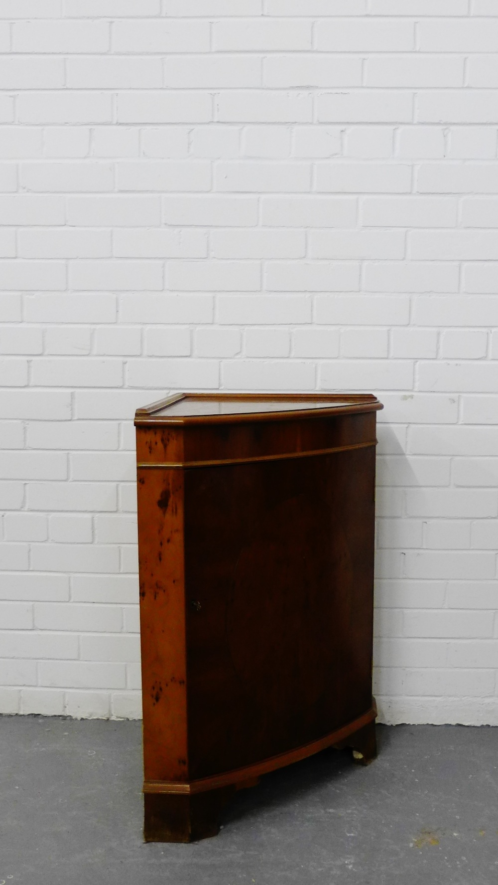 A contemporary yew wood corner cabinet with a cupboard base on bracket supports