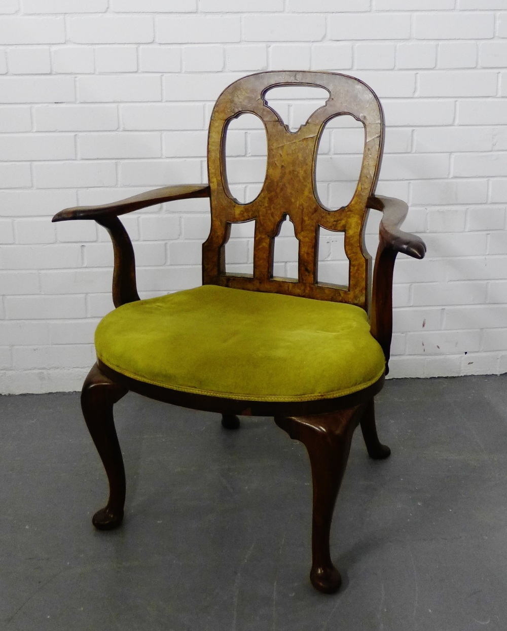 A walnut framed open armchair with pierced back, scrolling arms and upholstered seat on cabriole