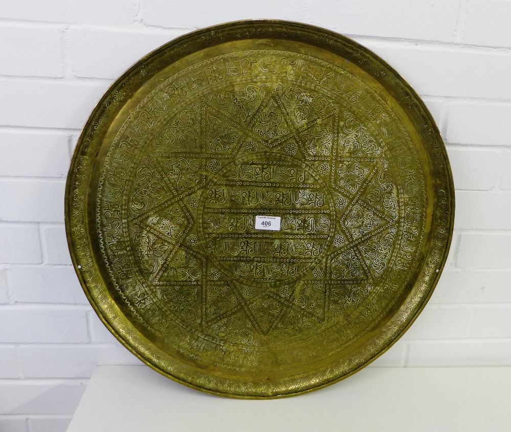 A Middle Eastern brass circular charger with calligraphy and foliate decoration, 59cm diameter