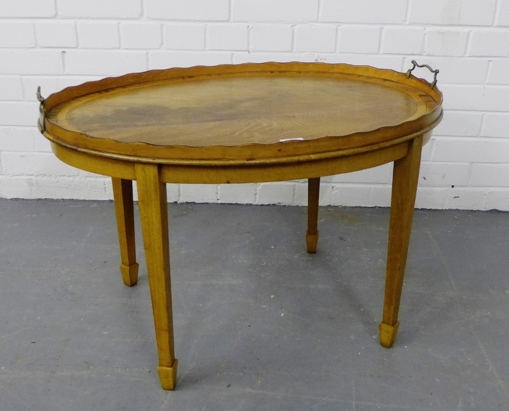 A mahogany tray top table of oval form, with twin brass handles, on tapering supports and spade