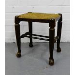 A mahogany stool with rush top seat on tapering supports, terminating in pad feet and ball supports,