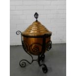 An Arts and Crafts copper coal bucket in a black iron scrolled support, 55cm