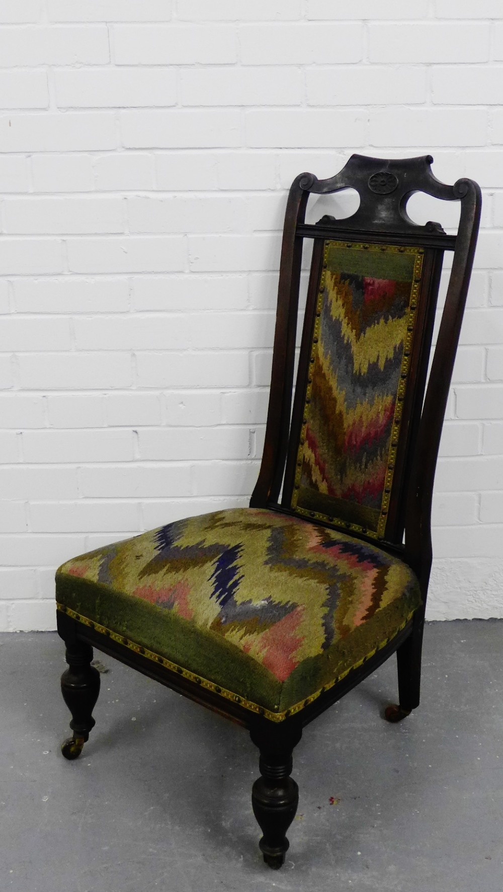 A mahogany framed nursing chair with a tapestry upholstered back and seat on turned supports