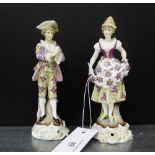 A pair of continental porcelain male and female figures, each modelled standing on Rococo style