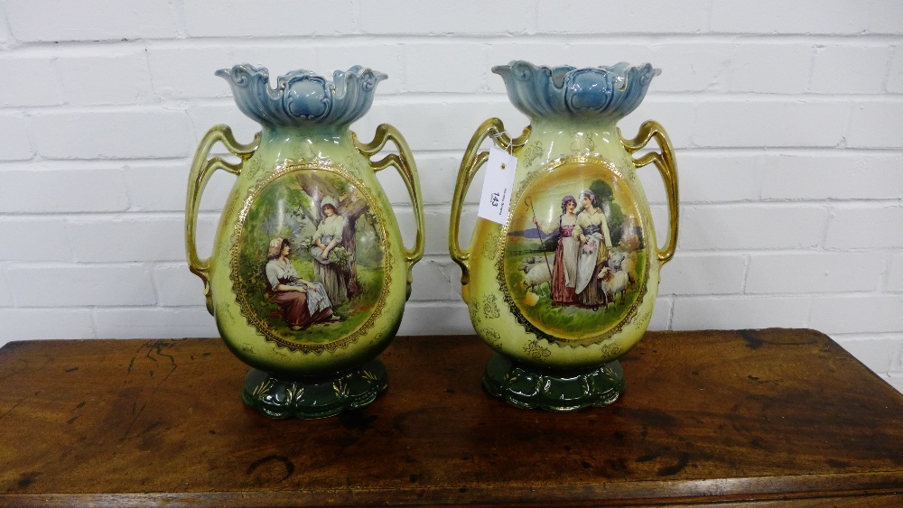 A pair of continental twin handled porcelain vases with gilt rims over painted panels depicting '