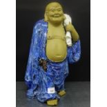 A Chinese partly glazed figure, modelled standing carrying a sack over his shoulder, 39cm high