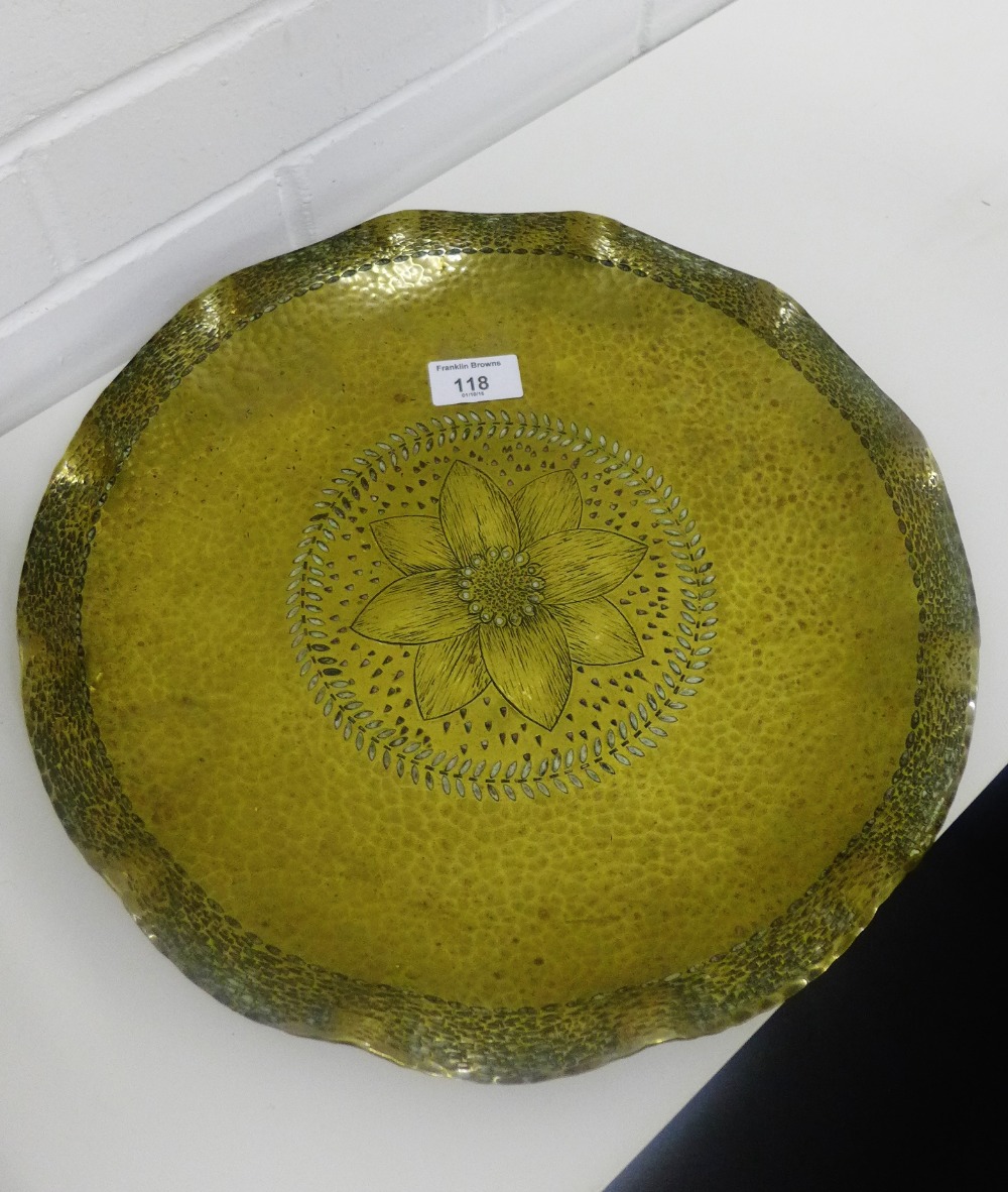 A German Arts & Crafts brass dish, the hand beaten finish with a floral decoration to the centre