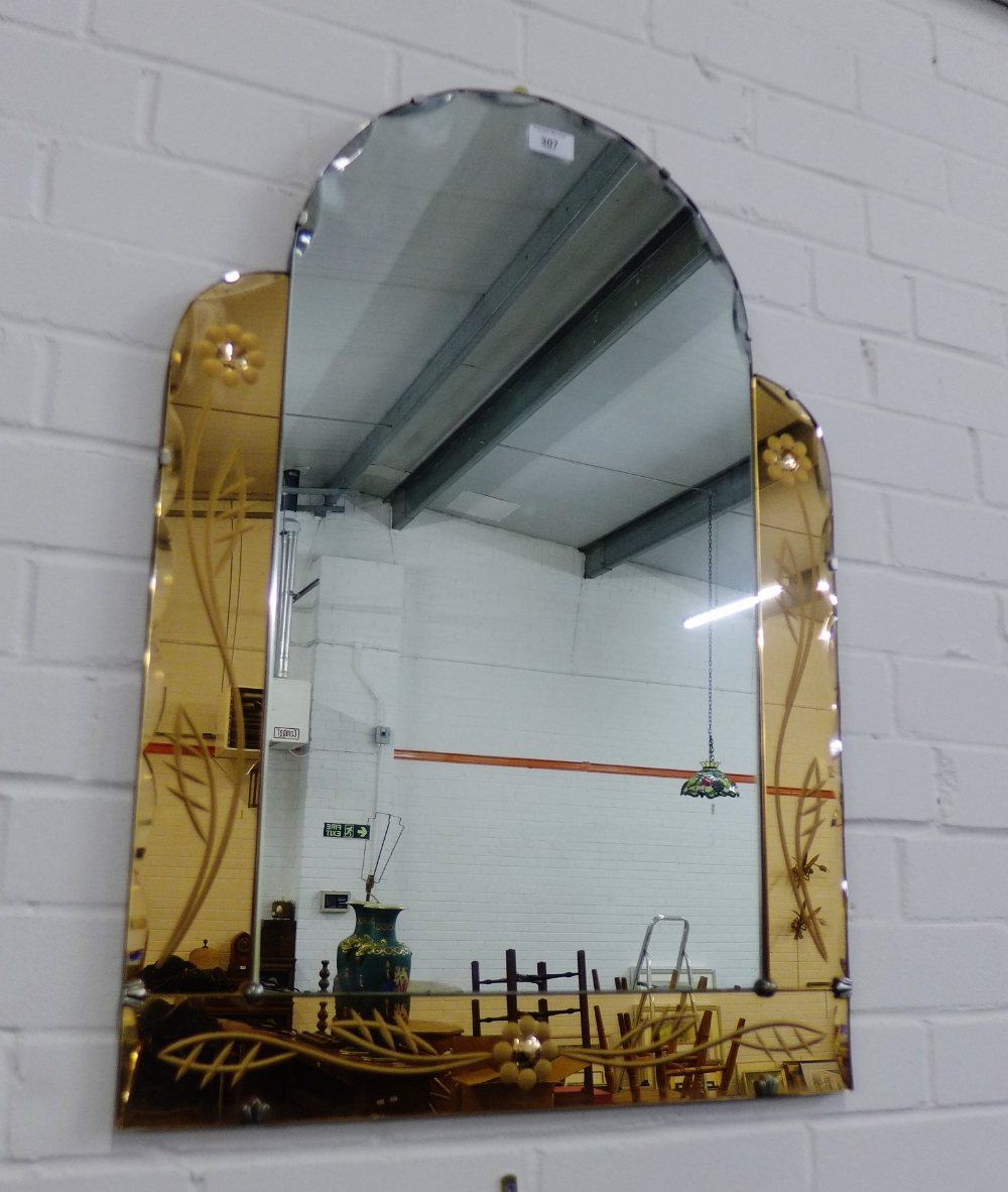 An Art Deco wall mirror, the central domed plate flanked by amber tinted and floral engraved glass