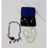 A mixed lot to include a strand of faux pearls, two tie pins and a garnet style necklace and