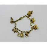 A 9ct gold bracelet, hung with an assortment of seven 9ct gold charms to include a gypsy caravan,