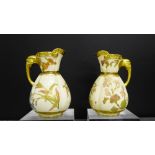 A pair of Royal Worcester blush ivory jugs with lion mask handles and gilt rims painted with