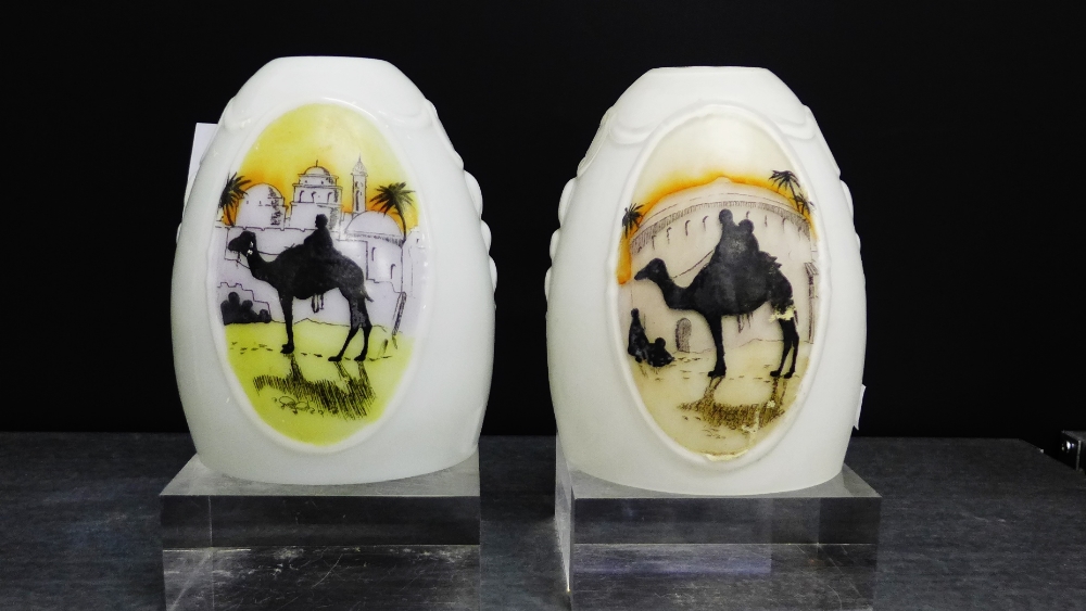 A pair of Hail Glass lamp shades, painted with a camel and dessert scene, 15cm high, (2)