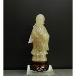 A chalcedony carving of an Immortal, modelled in standing pose with a bird to the left hand, on a