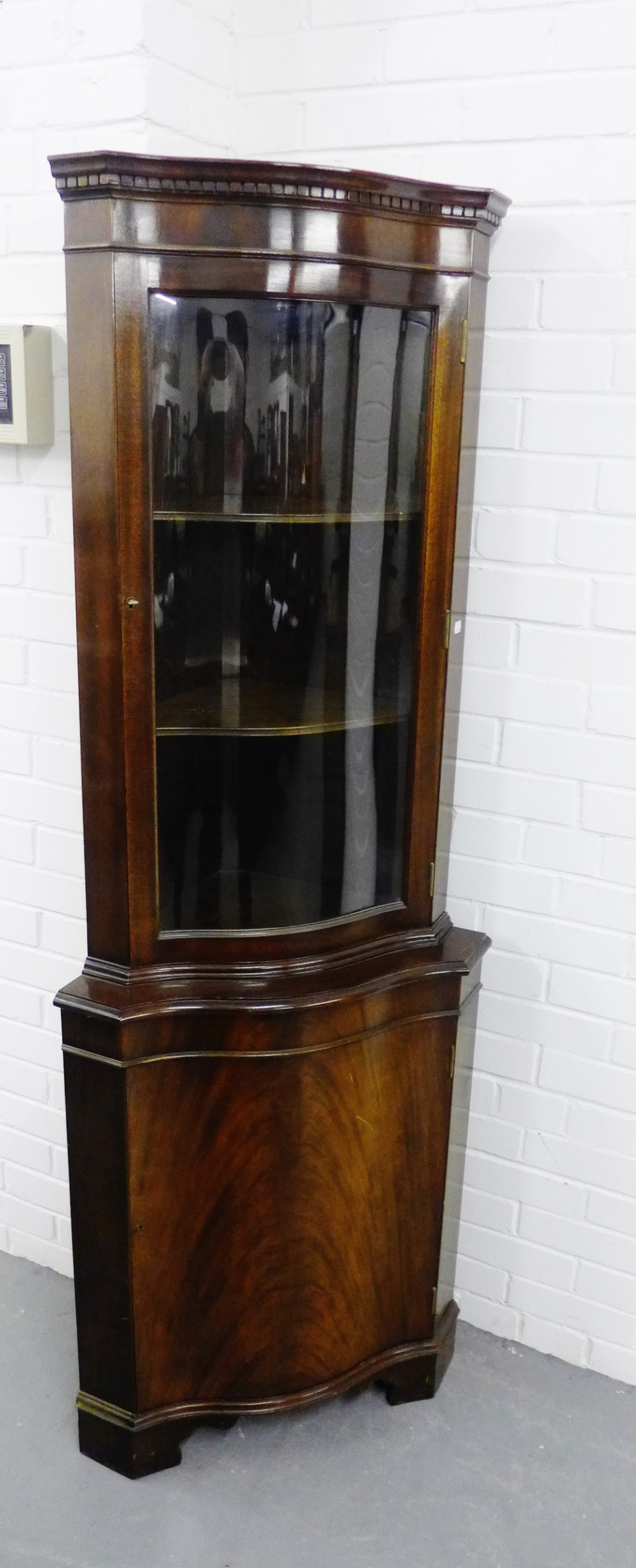 A mahogany corner cabinet, with a glazed door and shelved interior over a cupboard door to the base,