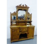 An oak sideboard, the carved broken pediment over with a mirror back, fitted a central drawer over