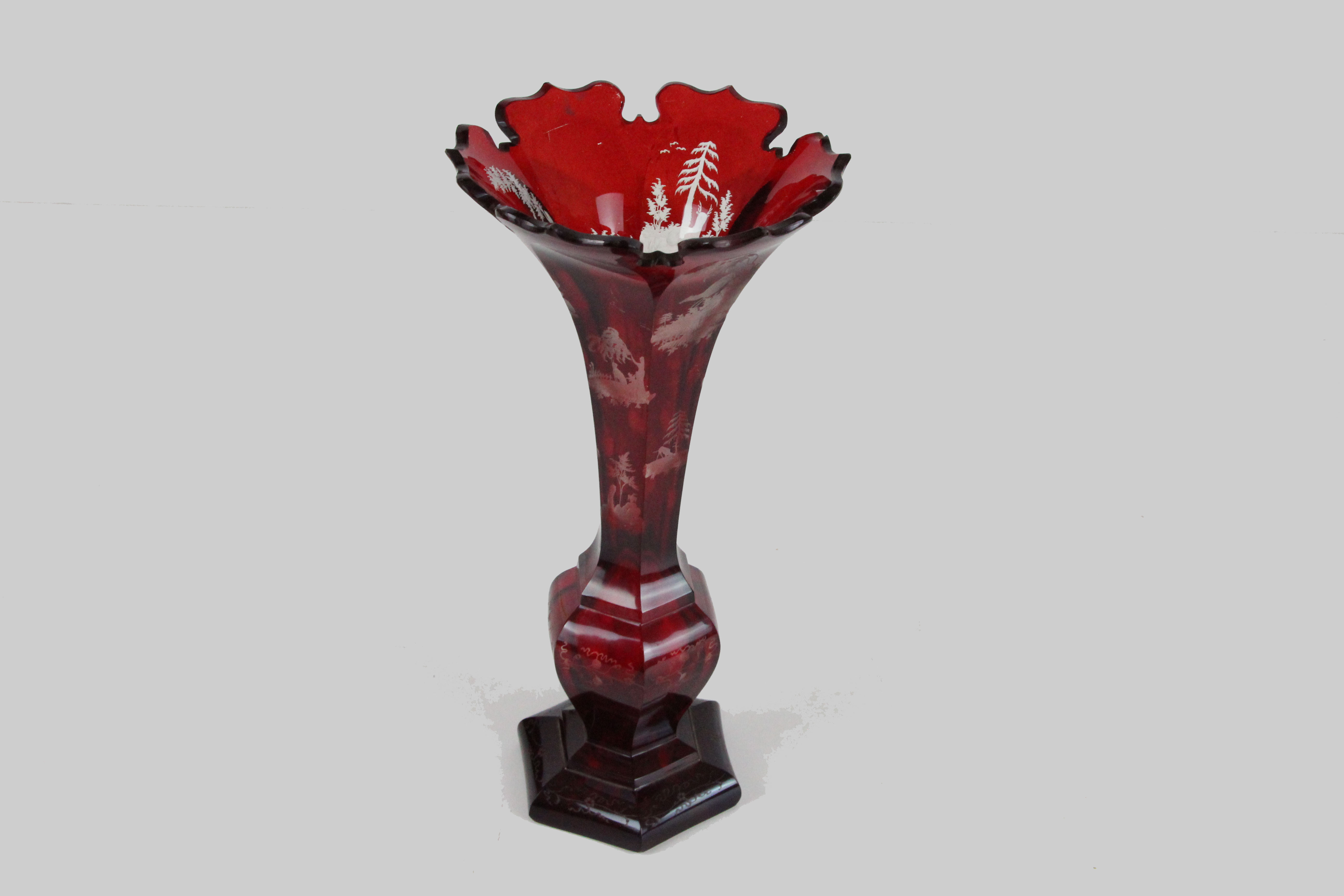 A Bohemian ruby flash glass trumpet vase cut through to clear with stags and trees, 26.5cm high