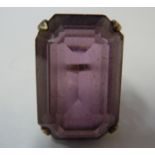 A vintage silver and cut cornered step cut amethyst coloured glass dress ring, set in white metal