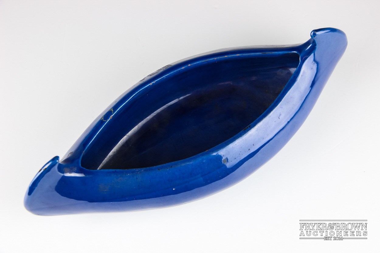 A C.H Brannam pottery model of a canoe, glazed in blue, incised mark, 29cm max approx