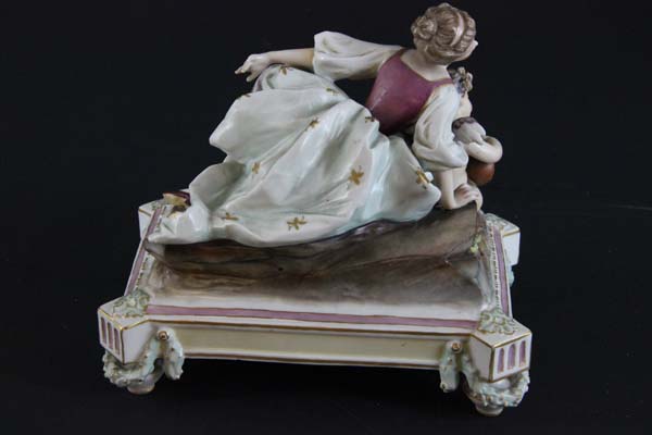 A Continental porcelain figure group of a young lady reclining with musical putto on plinth base - Image 2 of 3