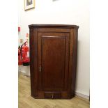An early 20th Century Oak hanging corner cupboards with solid opening onto 2 fixed shaped
