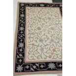 Cream ground needlepoint carpet with floral and foliate design, large black border with floral