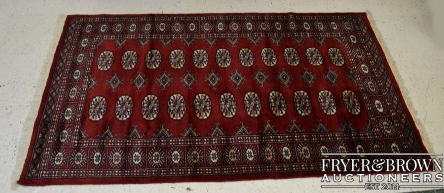 A modern Hamedan wool rug on cotton weft, claret ground with a design of medallions in black, pink