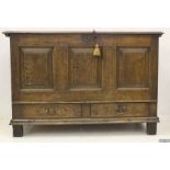 A large peg jointed oak three panel fronted coffer with two drawers under panels, with two plank