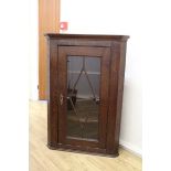 An early 20th Century oak hanging corner cupboards with astral glazed door opening onto 3 fixed