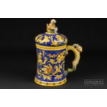 A Venetian maiolica tankard & cover, painted with grotesques and putti in ochre and yellow on a blue