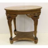A circular light mahogany centre table on four winged beast legs with shaped square undertier on