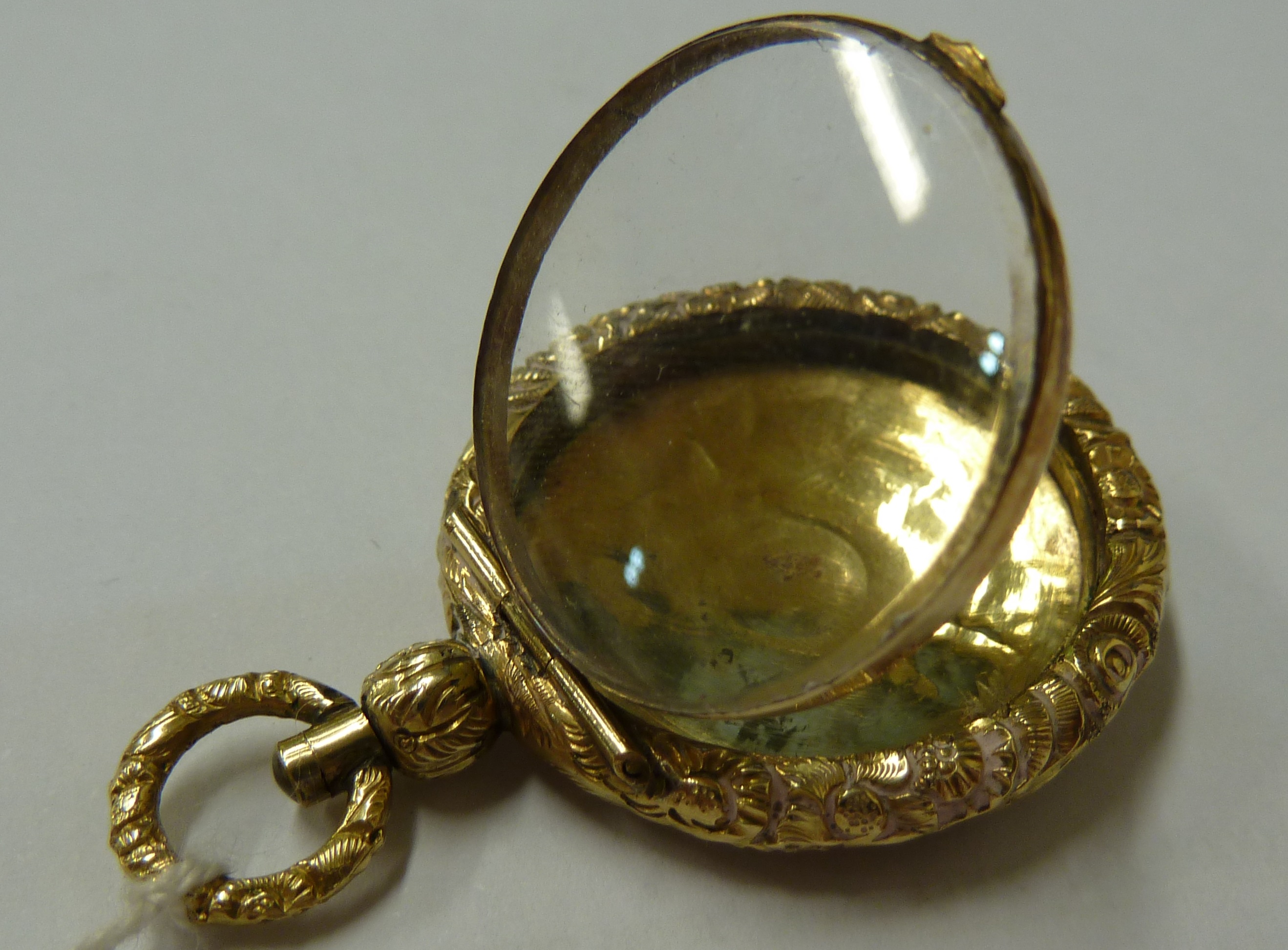 A small 15ct yellow gold locket, c1840, of circular form with carved floral borders - Image 4 of 7