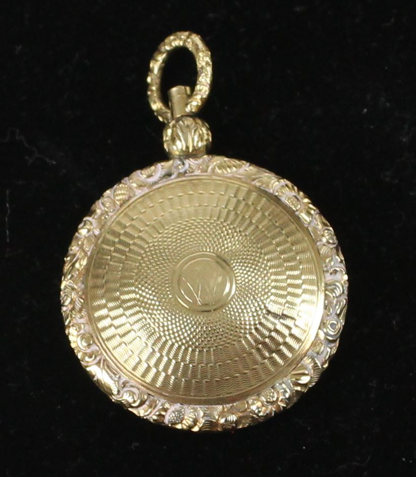 A small 15ct yellow gold locket, c1840, of circular form with carved floral borders