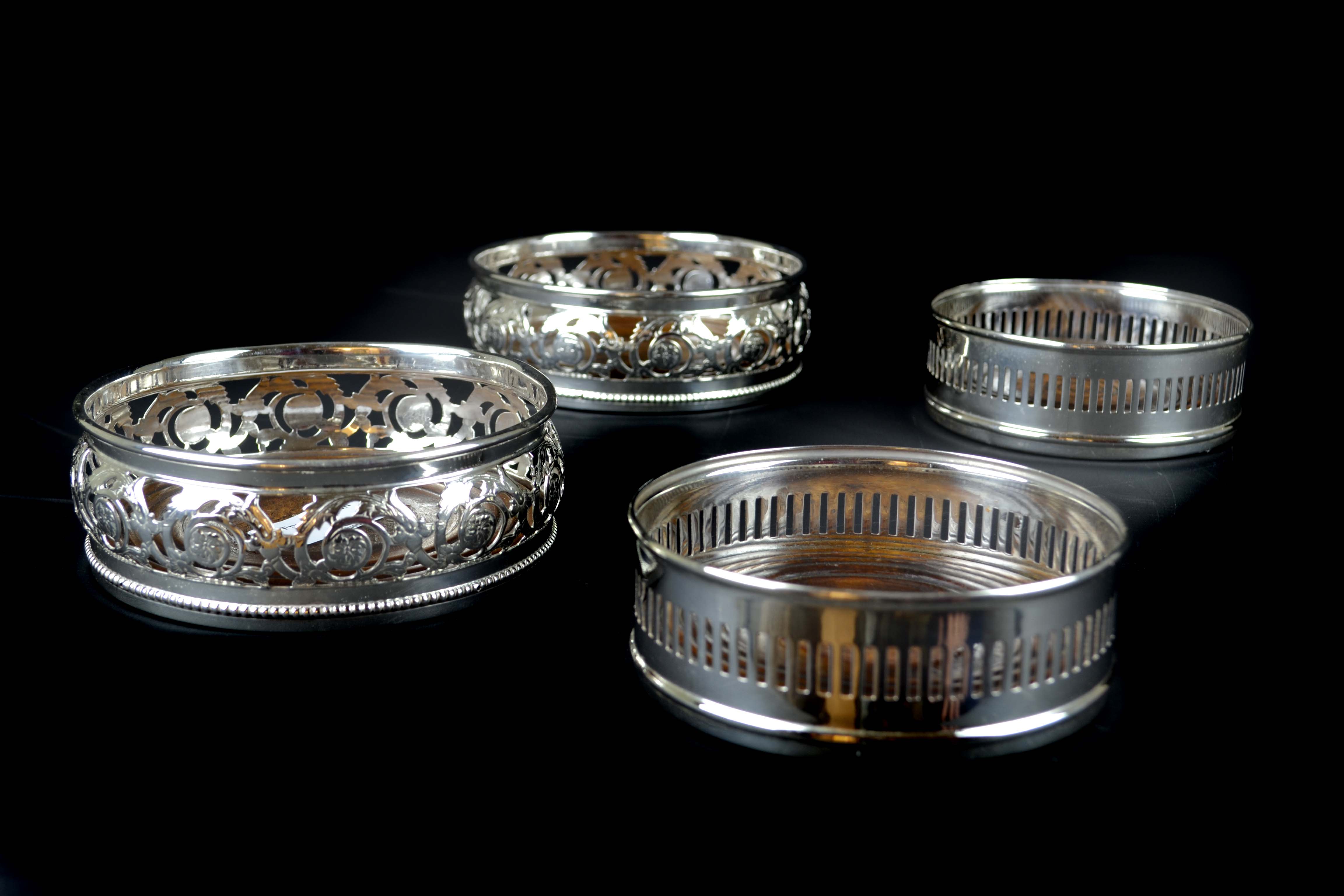 Two pairs of silver plated coasters, one pair of Regency style pierced with foliate scrolls; the